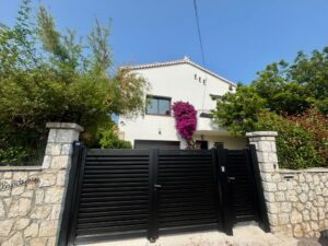 Photo La Bellaudiere Cagnes-sur-mer façade d'entrée avec portail et bougainvillier fleuri. Prise de l'impasse